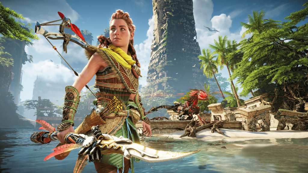 Aloy, the redheaded huntress protagonist of "Horizon: Forbidden West", stands on a tropical beach, posed for action. A ruined skyscraper draped in moss rises in the background. In the mid-ground, a robotic therapod with wicked red eyes stalks the rubble.
